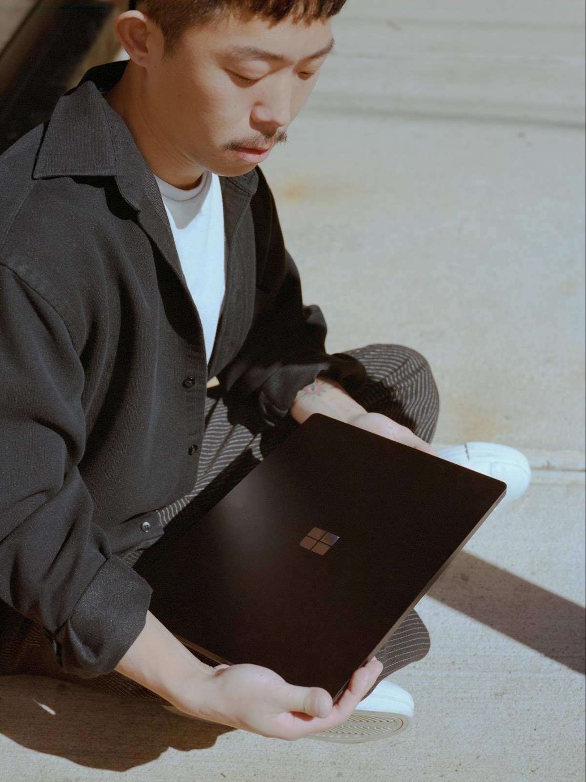 Business owner holding a laptop outdoors, representing the flexibility of managing digital campaigns remotely.