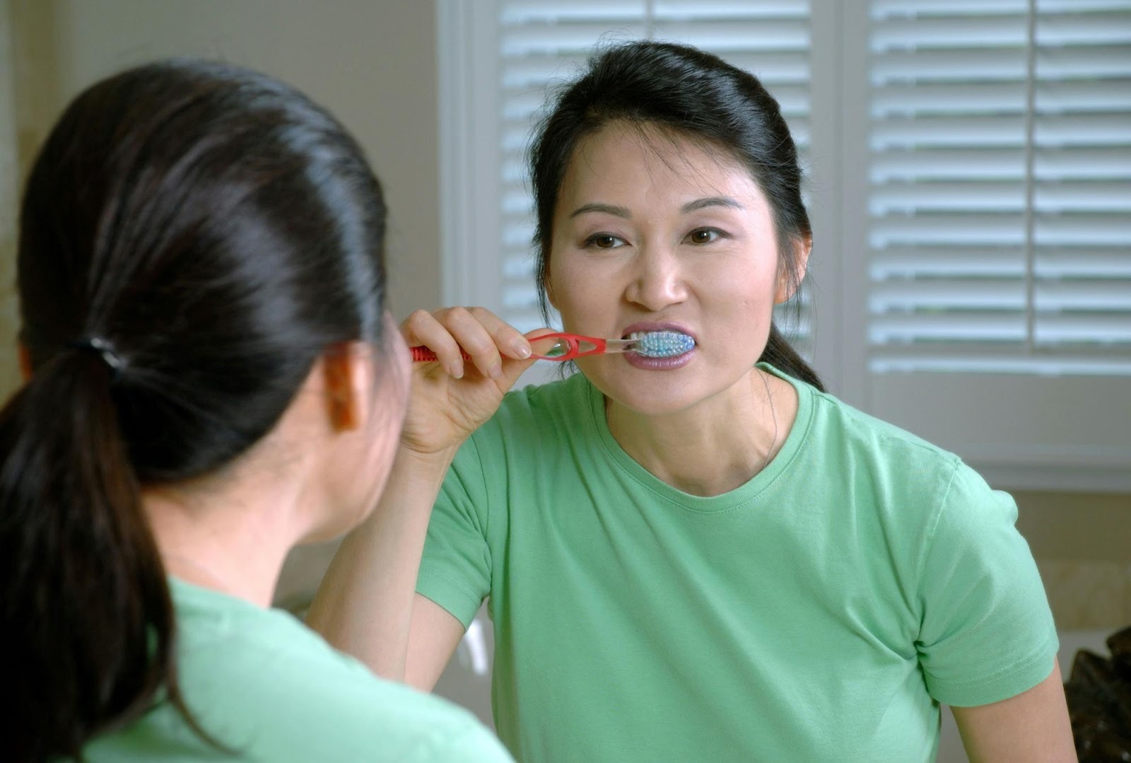 Woman brushing her teeth, suitable for educational blog posts about oral hygiene tips to engage current patients.