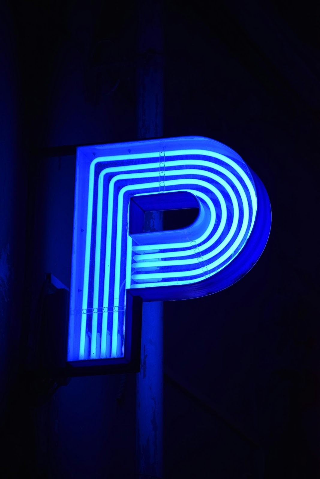Bright blue neon letter "P" sign, symbolizing the importance of physical branding and visual identity.